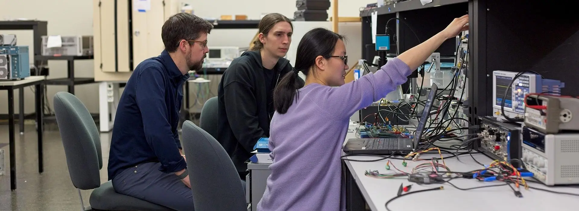 Doctoral students Jacob Dawes and Debbie Chou, under the guidance of Associate Professor Matt Johnston (left), test a setup to measure small particles as they pass through a microfluidic flow cell. 